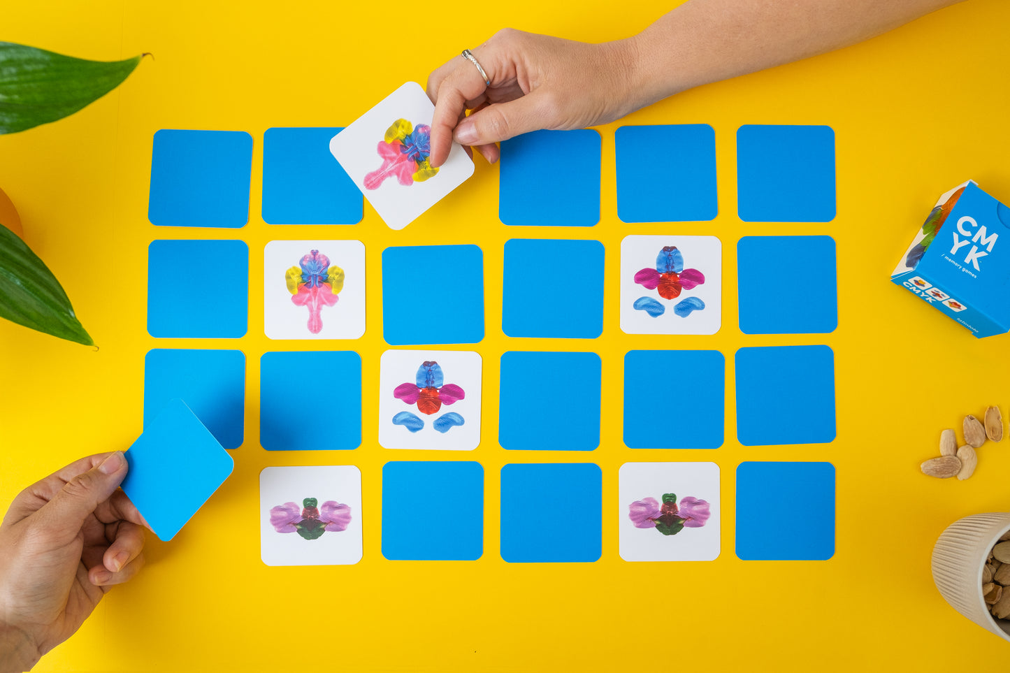 abstract memory game. Hands playing a matching game with colorful cards on a yellow background